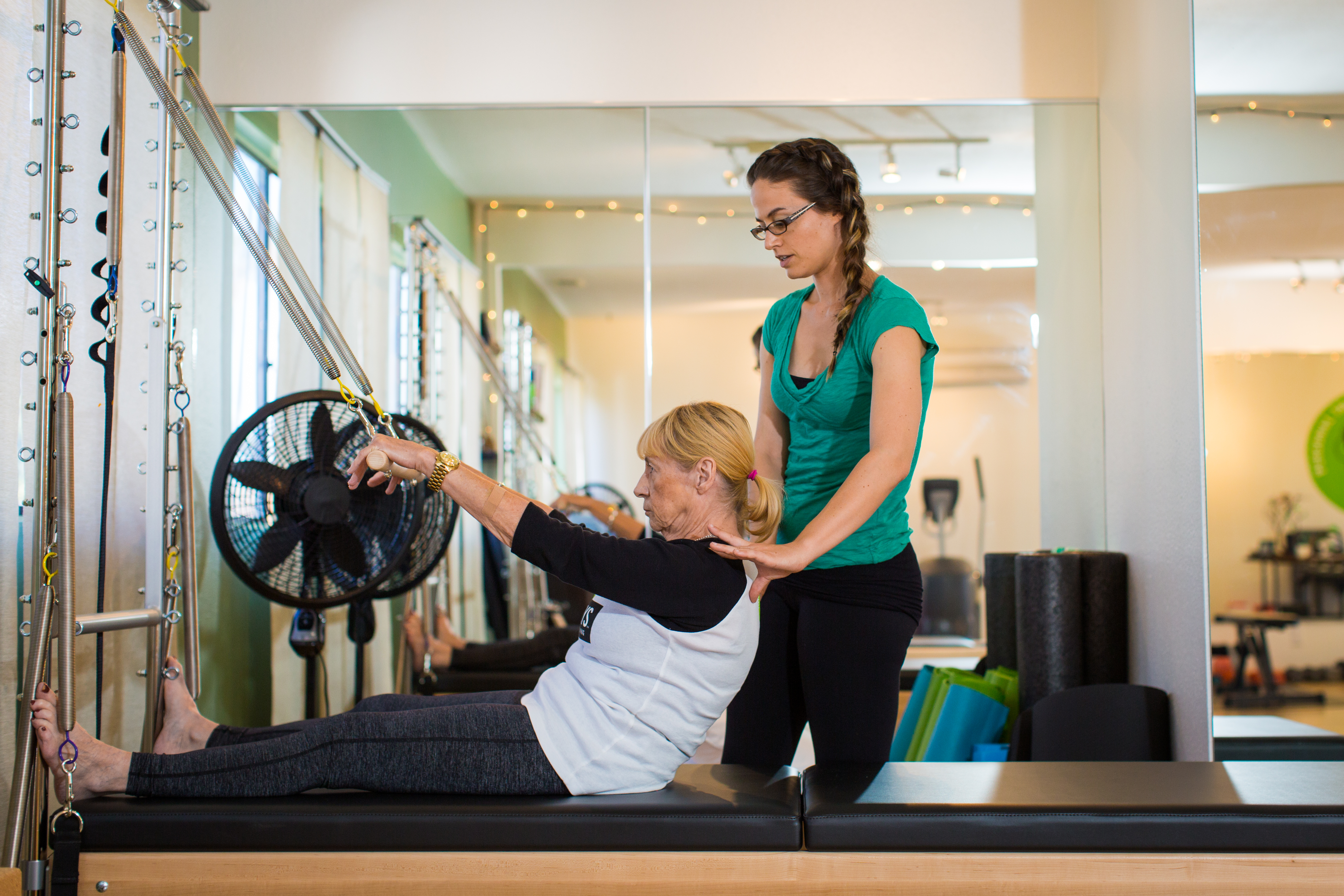 Fit Monkeys instructor coaching an older adult during a private Pilates session in the Carlsbad studio.